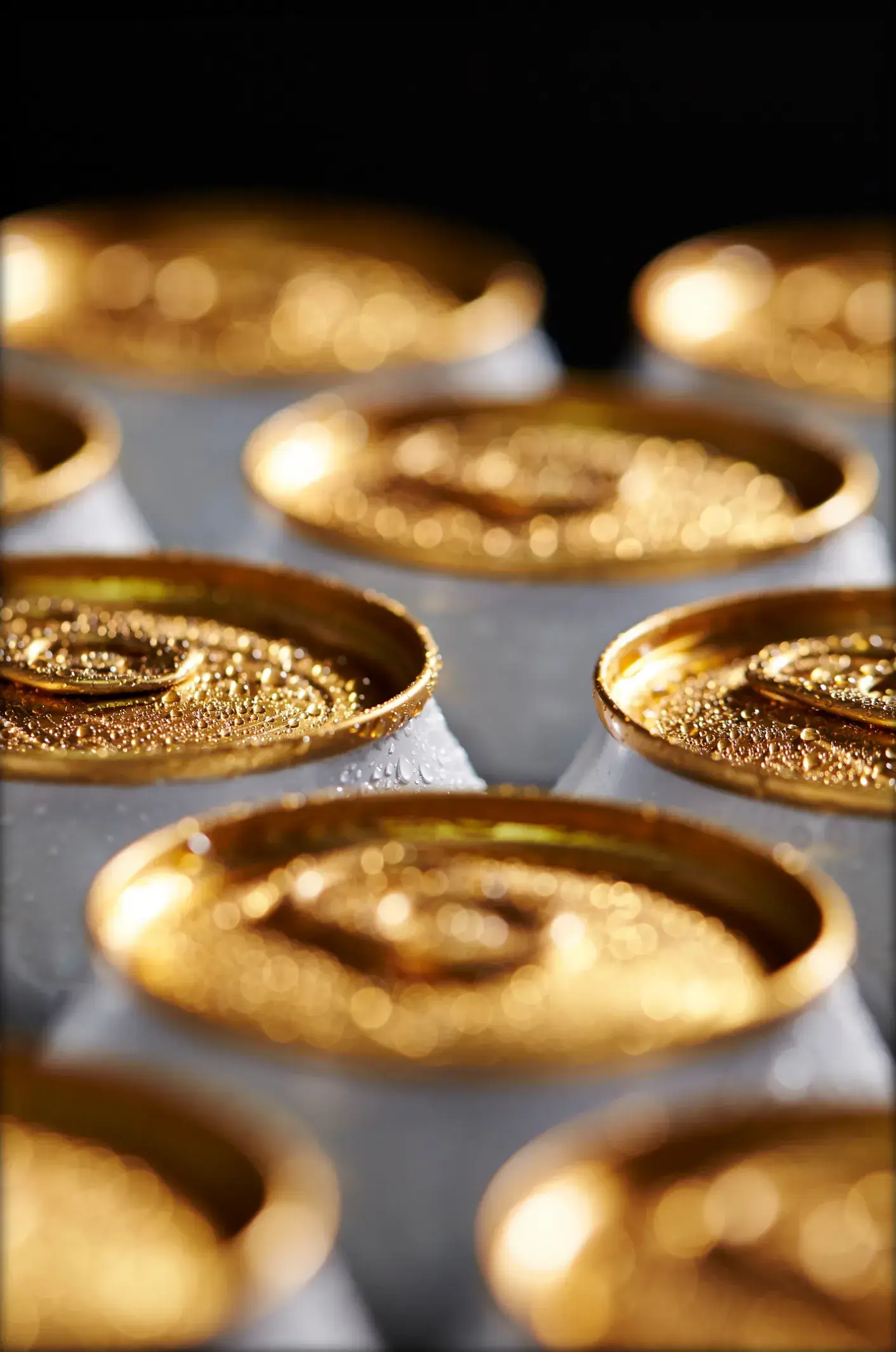 Close-up of golden bottle caps with condensation on a surface